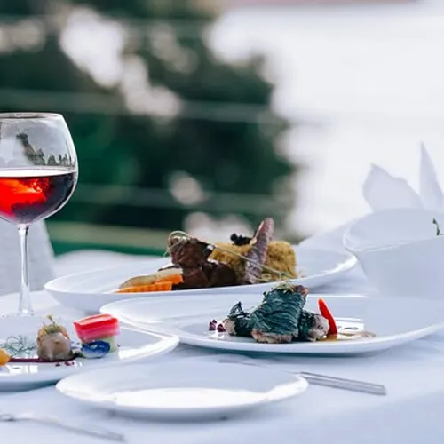 Set outdoors with scenic views of the Andaman Sea and Kata Beach, the table features several courses and a red wine glass